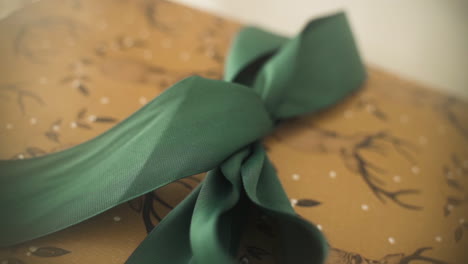 Close-up-push-in-on-Christmas-gift-adorned-with-deer-illustrations-and-a-big-green-bow