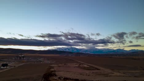 Colorful-cloudscape-over-the-distant-snowy-mountains---aerial-hyper-lapse