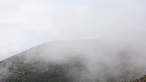 Clouds-moving-along-rocky-mountain-peak-during-foggy-day-after-hike