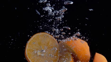 Orangen,-Die-Ins-Wasser-Fallen,-Superzeitlupe,-Schwarzer-Hintergrund,-Viele-Luftblasen,-4k240fps