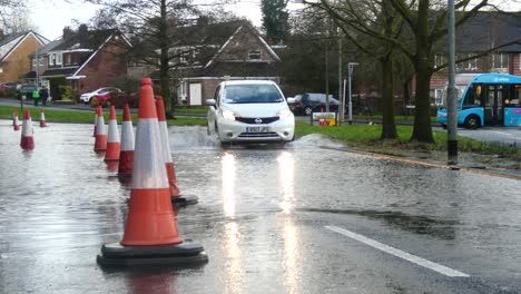 Storm-Christoph-white-car-driving-rainy-flooding-village-road-splashing-street-cones