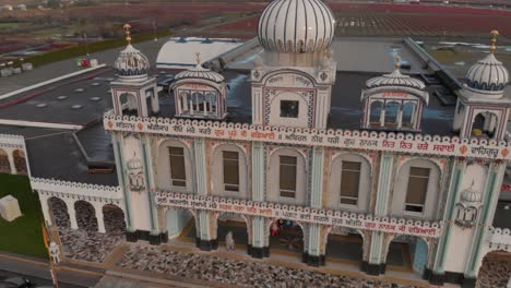 Drone-4K-Footage-revealing-front-facade-of-Hindu-temple-with-beautiful-and-elaborate-sculpture-and-symmetrical-architecture-in-the-middle-of-a-farmland-blueberry-fields-mountains-clouds