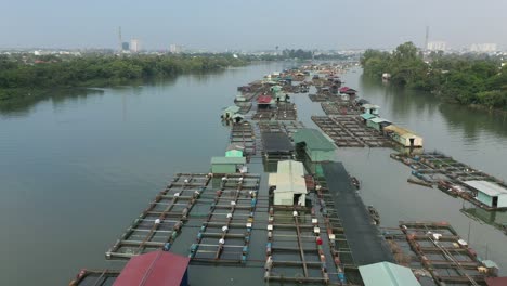 Drohnenschuss,-Der-An-Einem-Sonnigen-Tag-über-Die-Schwimmende-Fischzuchtgemeinschaft-In-Bien-Hoa-Am-Fluss-Dong-Nai,-Vietnam,-Fliegt