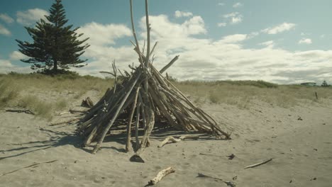 Branches-of-trees-making-a-pyramid-on-the-beach-for-a-bonfire
