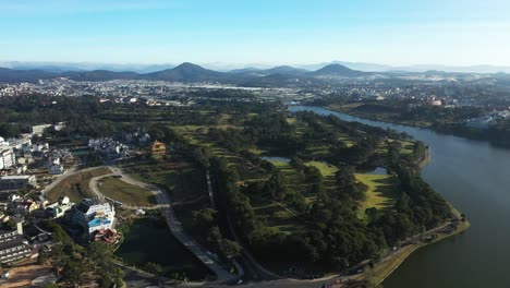 Golf-course-and-alpine-lake-in-Dalat,-Vietnam-from-drone-in-clear-early-morning-light
