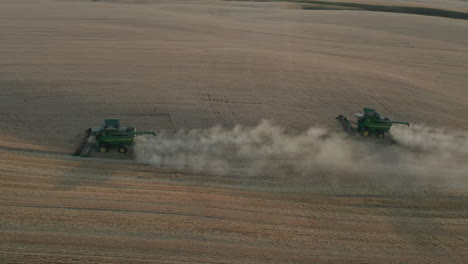 Side-panning-drone-view-of-two-harvesters-working-in-a-wheat-field-during-harvest