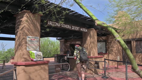 Caucasian-Man-With-Backpack-Enters-Arizona-Sonora-Desert-Museum-In-Tucson,-Arizona-On-A-Sunny-Day