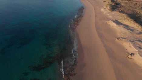 Aerial-tilt-up-reveal-over-Matadouro-golden-beach-at-sunrise