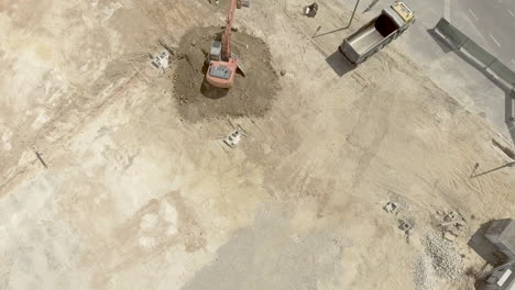 Backhoe-At-Work---Scooping-Excavated-Soil-At-The-Construction-Site---pullback-drone-shot