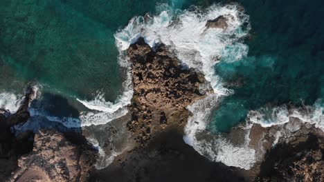 Top-down-lowering-over-ocean-waves-crashing-on-rocky-coast-near-Porto-dos-Frades,-Madeira
