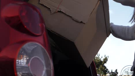 Woman-taking-cardboard-box-out-of-car-boot-low-medium-shot