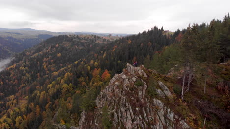 Aerial-view-of-a-rock-in-the-middle-of-a-valley-filled-with-autumn-color-tree-forest-in-Transylvania,-Romania,-Orbit-shot