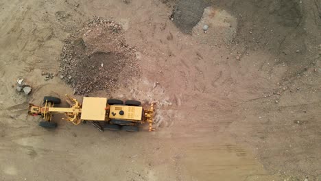 Aerial-flyover-of-a-construction-grader-in-a-dirt-lot