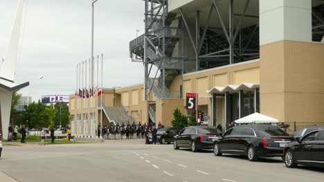 Canadian-military-funeral-ceremony-outside-sports-stadium,-black-limousines-parked