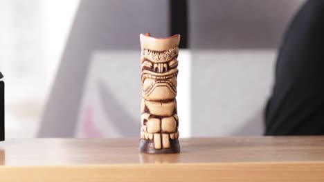 Barman-Adds-A-Cinnamon-Stick-To-Cocktail-Drink-Served-In-A-Wooden-Tiki-At-The-Bar-Counter---close-up,-slow-motion