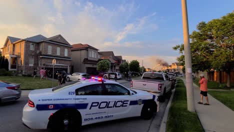 Scene-of-a-neighborhood-house-fire-with-a-police-car-in-the-foreground