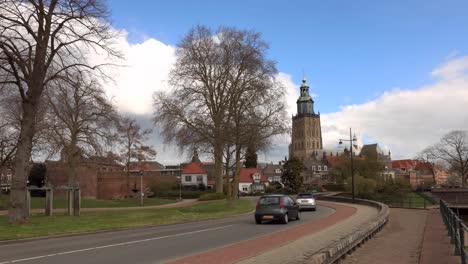 Time-lapse-of-cars-on-meandering-bending-town-road-with-Walburgiskerk-cathedral-towering-behind-against-a-blue-sky-with-ominous-clouds-developing-above