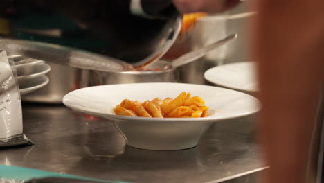 Plating-Freshly-Cooked-Penne-Pasta-At-The-Restaurant-Kitchen-For-Serving---close-up,-slow-motion