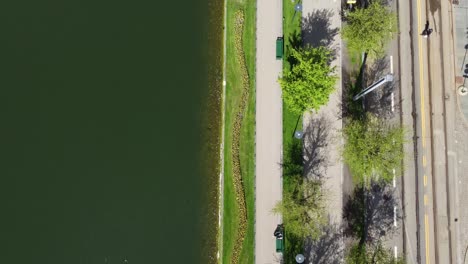 Forward-moving-aerial-of-park-with-people-walking-and-pond-with-water-close-to-railroad---Lungegaard-Bergen-split-screen