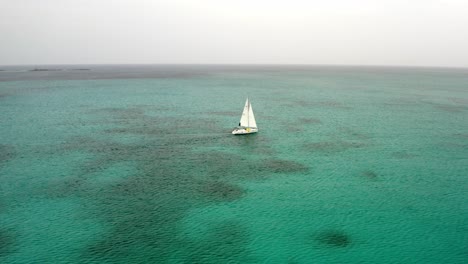Aerial-View-of-Sailboat-in-Open-Tropical-Sea-Sailing-To-Horizon,-Drone-Shot