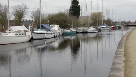 Small-sailboats-moored-on-peaceful-rural-countryside-canal-marina