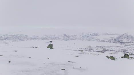 People-Exploring-Vast-Snowy-Mountains-In-Huagastol-Norway---aerial-panning-shot