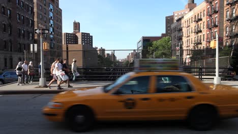 New-York-City-street-with-passing-people-and-cars-on-a-sunny-evening