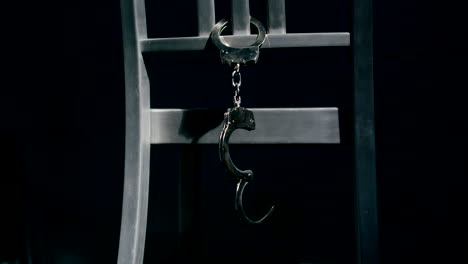 Slow-motion-medium-tracking-shot-of-a-pair-of-handcuffs-dangling-from-the-back-of-a-chair