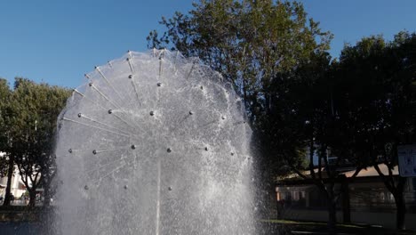 Slowly-rotating-around-dandelion-shaped-water-fountain-in-Hlavaty-Park-in-Koper,-Slovenia