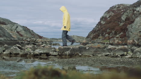Woman-in-yellow-raincoat-walks-over-nature-stonebridge