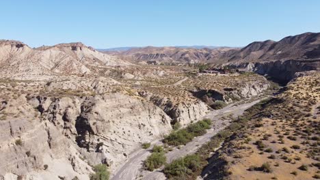 Tabernas-Desert-in-Almeria,-Andalusia,-Spain---Aerial-Drone-View-of-the-road-to-Theme-Park-Western-Leone,-Dry-Valley-and-River-Bed
