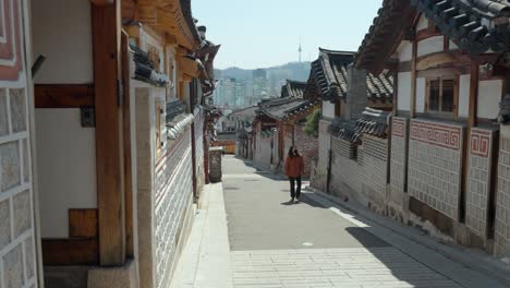Frau,-Die-Die-Traditionelle-Koreanische-Architektur-Des-Hanok-Dorfes-Bukchon-Besichtigt,-Blick-Auf-Den-Namsan-N-Seoul-Turm-In-Südkorea