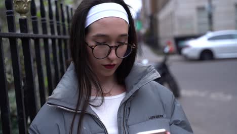 Beautiful-young-woman-using-her-cell,-mobile-phone-in-Soho,-London,-close-up
