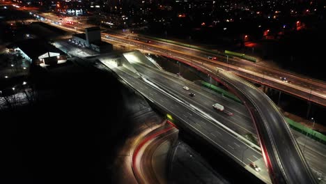 Drone-shot-of-night-traffic-on-a-motorway-showing-cars-and-lanes-of-light-with-Tunnel-and-viaducts-outside-the-city-of-Warsaw,-Poland