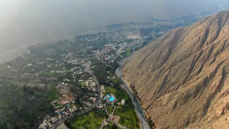 Flying-over-Santa-Eulalia-town-between-steep-mountains-in-Huarochiri,-Peru