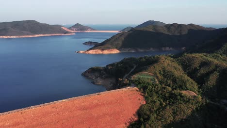 Vorwärts-Bewegte-Luftaufnahme-über-Einem-Damm,-Der-Gebaut-Wurde,-Um-Die-Gruppe-Der-Bewohnten-Inseln-Im-Hong-Kong-Geopark-In-Sai-Kung-Bei-Sonnenuntergang-Zu-Verbinden