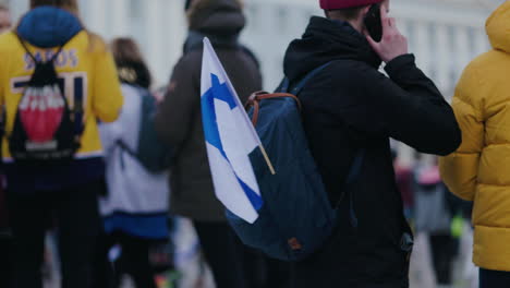 Person-wearing-a-backpack-with-a-Finnish-flag---Olympic-Ice-hockey-gold-celebration-in-Helsinki,-Finland