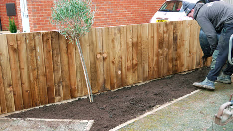 Landscape-Gardner-Applying-Topsoil-To-His-Work,-Completed-Work-With-Brand-New-Fence