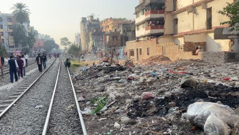 Verstreuter-Müll-Neben-Leeren-Bahngleisen,-An-Dem-Menschen-In-Dhaka-Entlanglaufen