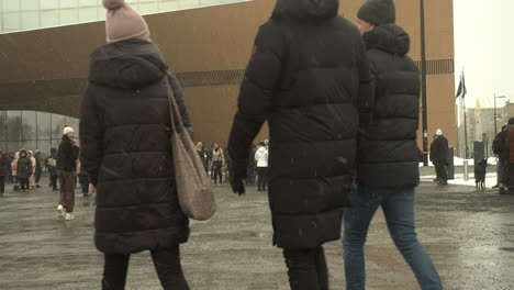 Wide-shot-of-people-walking-towards-citizen-square-for-the-Helsinki-covid-19-protests,-cold-snowy-day