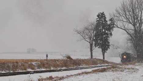 An-Antique-Restored-Locomotive-and-Passenger-Coaches-Approaching-During-a-Snow-Storm-Blowing-Smoke-and-Steam-Traveling-Thru-the-Countryside