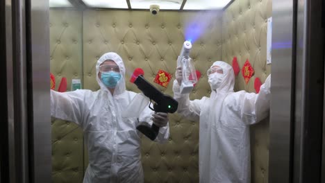 Employees-wearing-PPE-spray-disinfectant-into-an-elevator-at-a-spa-facility-as-prevention-against-Covid-19-virus-during-its-reopening-in-Hong-Kong