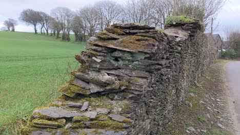 An-ancient-stonewall-near-the-road-with-a-distant-view-over-farm-house