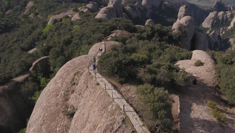 Breathtaking-aerial-view-of-Montserrat-mountain-range-in-Spain,-tourists-and-runners-admiring-panorama