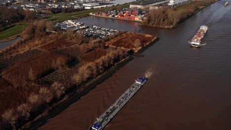 Drohnenansicht-Von-Zwei-Schiffen,-Die-Den-Eingang-Zum-Yachthafen-Entlang-Des-Flusses-Noord-Passieren