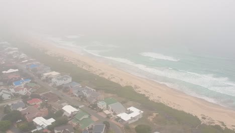 Rising-drone-shot-of-vacation-beach-town,-rising-into-clouds