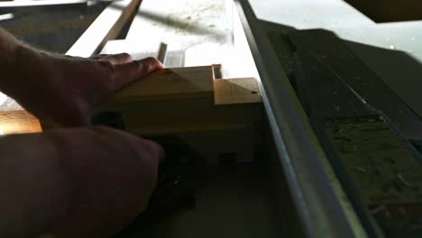A-woodworker-places-a-piece-of-wood-on-a-table-saw-with-a-stacked-dado-set-and-pushes-it-through-to-make-multiple-cuts-to-create-a-tenon-in-slow-motion
