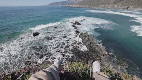 POV-sitting-on-the-edge-of-a-cliff,-looking-out-on-the-coast-and-ocean