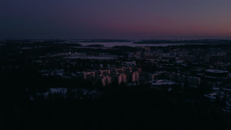 Forward-aerial-of-forest-and-snowy-neighborhood-in-Finland-at-dusk
