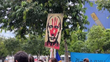 Teleaufnahme-Eines-Plakats,-Das-Von-Einem-Friedlichen-Demonstranten-Auf-Dem-Brisbane-Square-Gehalten-Wird-Und-Eine-Blutige-Handsilhouette-Auf-Wladimir-Putins-Gesicht-Zeigt,-Die-Die-Unmenschlichen-Massaker-Des-Russischen-Militärs-Zum-Ausdruck-Bringt